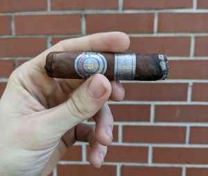 Hand holding a Montecristo Platinum Series Rothchilde Tube cigar